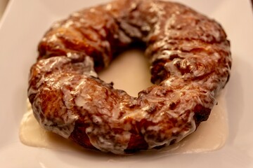 Large doughnut served as a cake on a white plate with a vanilla glaze