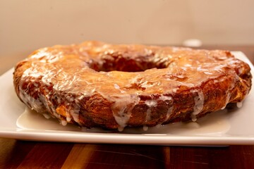 Large doughnut served as a cake on a white plate with a vanilla glaze
