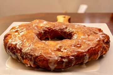 Large doughnut served as a cake on a white plate with a vanilla glaze