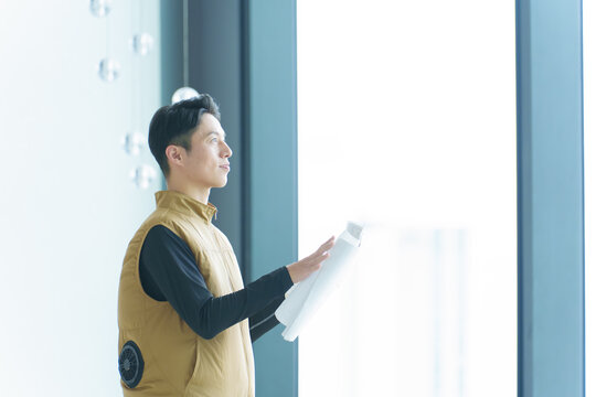 図面をチェックするファンベストを着た作業員