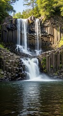 Long exposure waterfall on dark basalt cliffs. Silky smooth water texture in a serene landscape. Reflective foreground with a cascading waterfall.