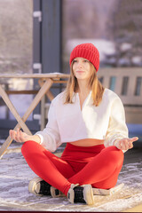 Amidst a winter wonderland, a woman sits peacefully in a meditative pose, dressed in warm attire. Her serene expression reflects a deep sense of zen as she embraces the chilly air.