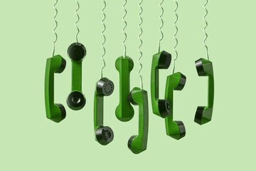 Hanging green telephone handsets on light background