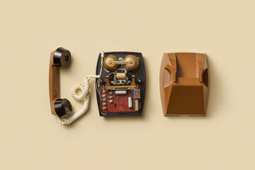 Disassembled vintage telephone on beige background