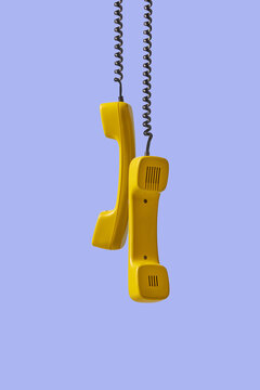 Two yellow telephone handsets with cords on violet