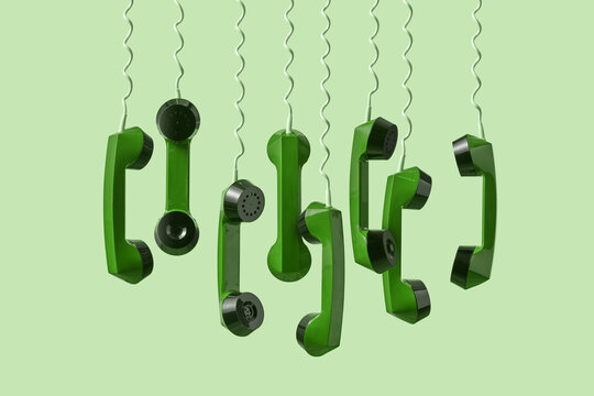 Hanging green telephone handsets on light background