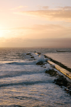 a wave breaker in portugal during sunset