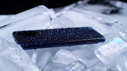 A closeup shot of a modern smartphone covered in water droplets resting on a bed of ice cubes highlighting its waterproof and durable features in a cool refreshing setting. - Powered by Adobe