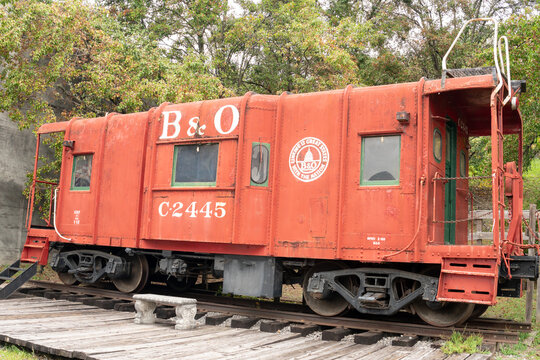 Grafton, West Virginia - October 14, 2021: historic steel B&O railroad caboose painted bright red and sitting on a small section of rail in display on Main Street in the center of town