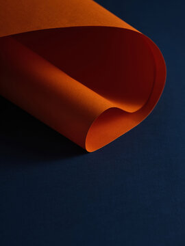 Close-up of orange paper curling over a textured blue