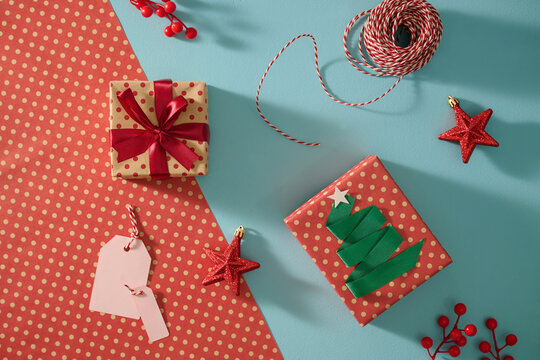 Christmas presents and ornaments arranged on a blue and red backdrop.