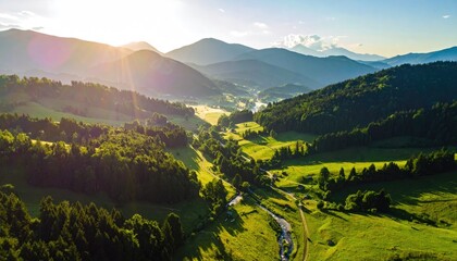 Lush Green Valley With A Winding River Under Golden Sunrise Rays Illuminating Distant Hazy Mountains And Forested Hills With Lens Flare Effect