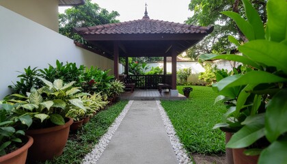 A serene garden pathway leading to a traditional wooden gazebo, surrounded by lush tropical plants and well-maintained greenery, creating a peaceful outdoor retreat