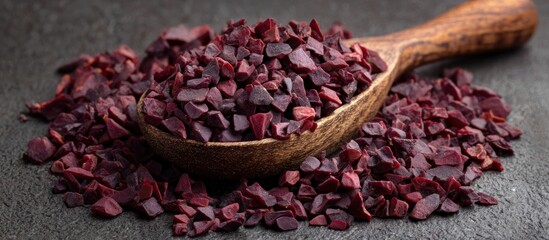 Pile of chopped red root pieces with a wooden spoon on a gray background