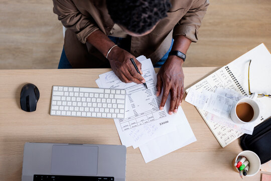Person reviews invoices at desk with laptop and coffee.