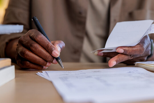 Person reviews receipts and documents with pen in hand.