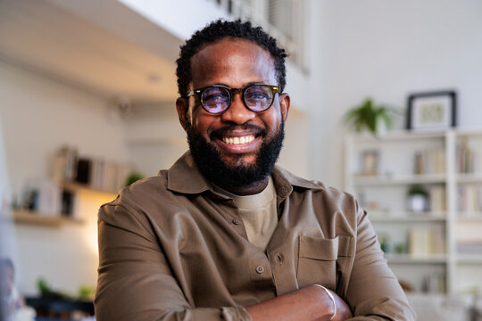 Smiling man with glasses and arms crossed.