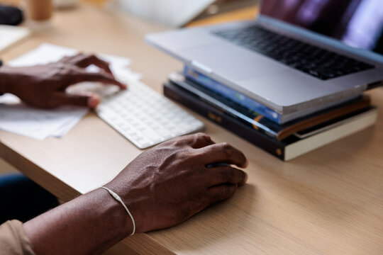 Hands type on keyboard, laptop on books.