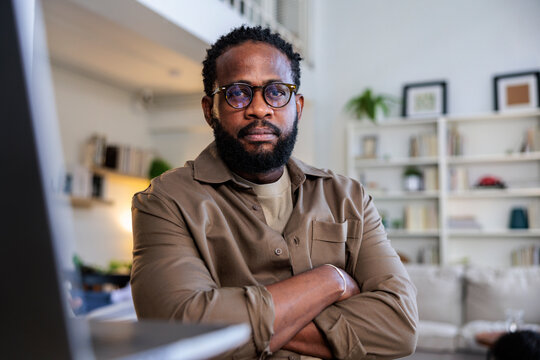 Portrait of a man with glasses, arms crossed.