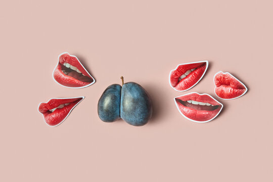 Split plum with red lips cutouts on pink surface
