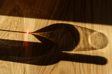Shadow of wine bottle and glass on wooden floor with red light reflect