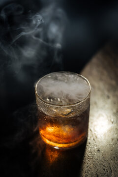 Smoky cocktail in textured glass on bar counter