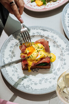 Cutting into eggs benedict on toast with runny yolk