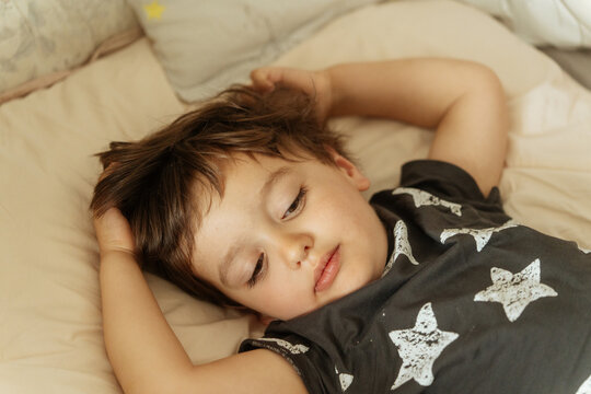 Child lying in bed with star-patterned shirt
