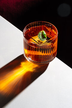 Amber cocktail with mint on white table