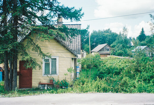 Small Yellow Cottage Surrounded by Greenery in Rural Setting