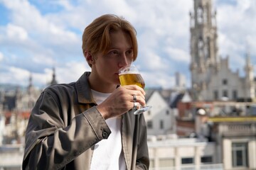 Young Man Enjoying Craft Beer With City Skyline View
