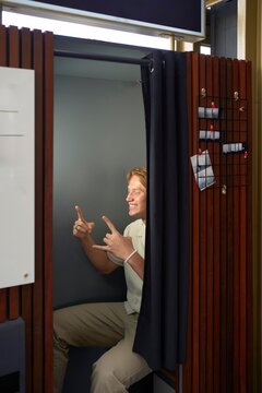 Man Posing in a Photo Booth With Playful Hand Gestures Indoors