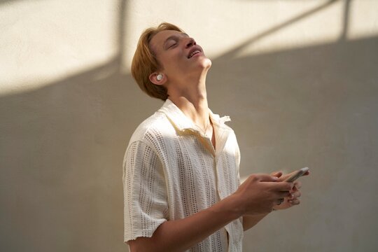 Young Man Enjoying Music With Earbuds in a Bright, Stylish Room