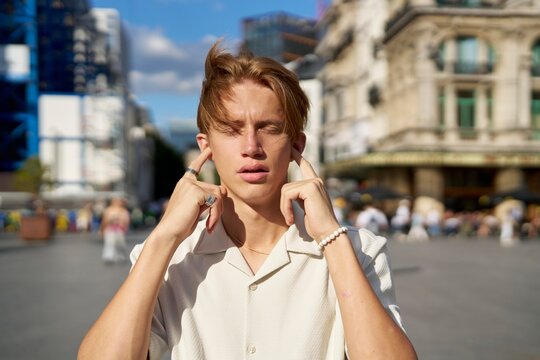 Young Man Enjoys Quiet Moment in Busy Urban Square Under Sunlight