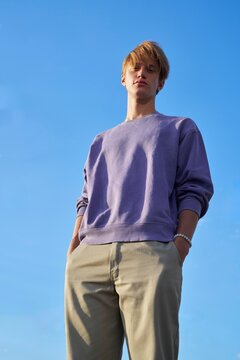 Young Man Poses Confidently Under a Blue Sky