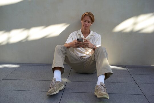 Young Man Enjoys Leisure Time While Texting in a Sunny Spot