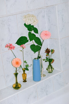 Minimal floral arrangement in small vases on tiled background