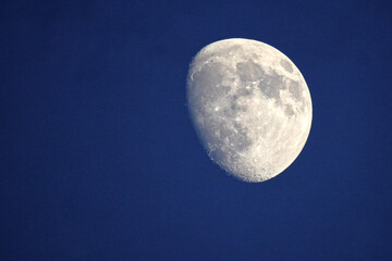 Craters of the moon on display on full moon in blue night sky. 