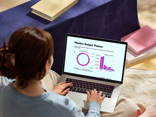 A woman works on a laptop, reviewing and managing her finances