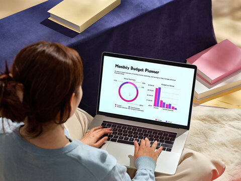 A woman works on a laptop, reviewing and managing her finances
