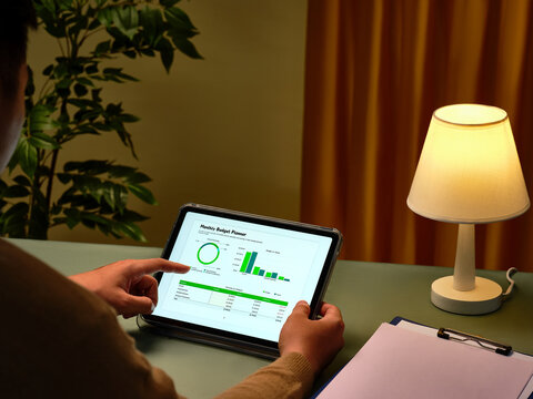 Someone reviews a financial budget planner displayed on digital tablet