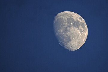 Craters of the moon on display on full moon in blue night sky. 