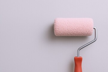 Obraz premium Paint roller with pink color on clean wall background, house renovation and painting service concept