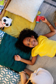 Girl smiles, plays with toy hair dryer on rug 