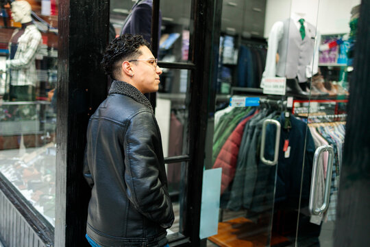 Young man looking at menswear display through shop window