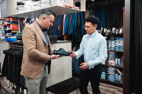 Vendor handing formal shoe to customer during fitting in store