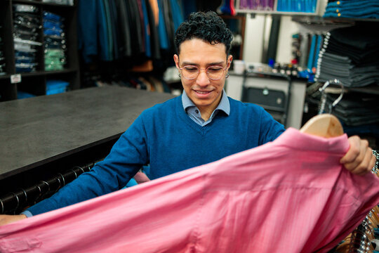 Customer inspecting pink shirt in menswear boutique