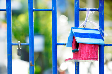 Colorful Birdhouse Hanging on Blue Gate with Soft Background