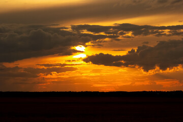 Beautiful bright orange and dark blue sunset light in prairies. Agricultural field in warm autumn idyllic atmosphere after dark.