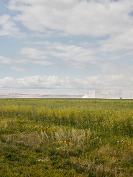 Potash plant beyond prairie field under cloudy sky